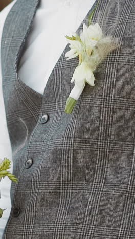 elegant young man in grey vest with boutonniere and fresh flowers before wedding ceremony in palace closeup. marriage ceremony for new family