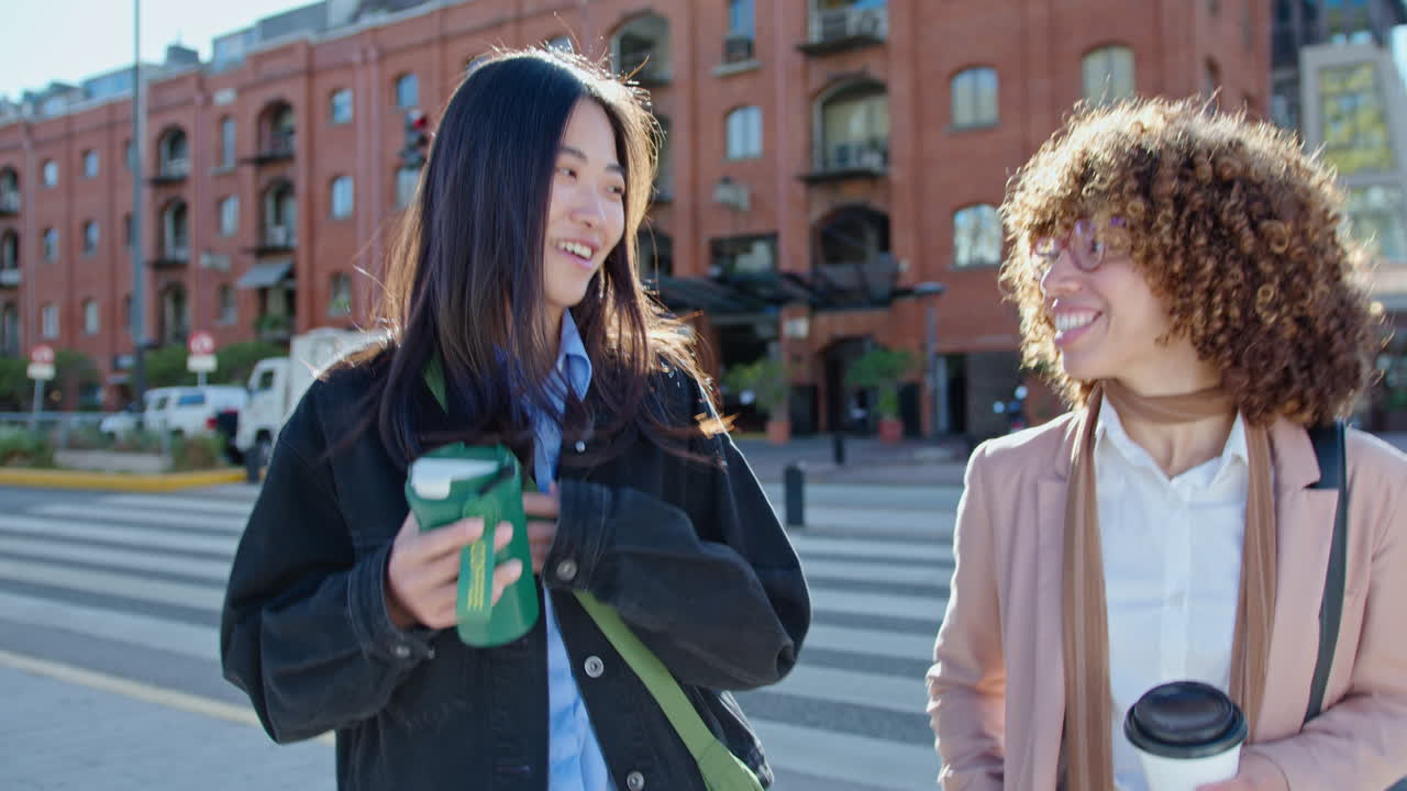 Young Cheerful Women Walking on City Street with Coffee and Talking