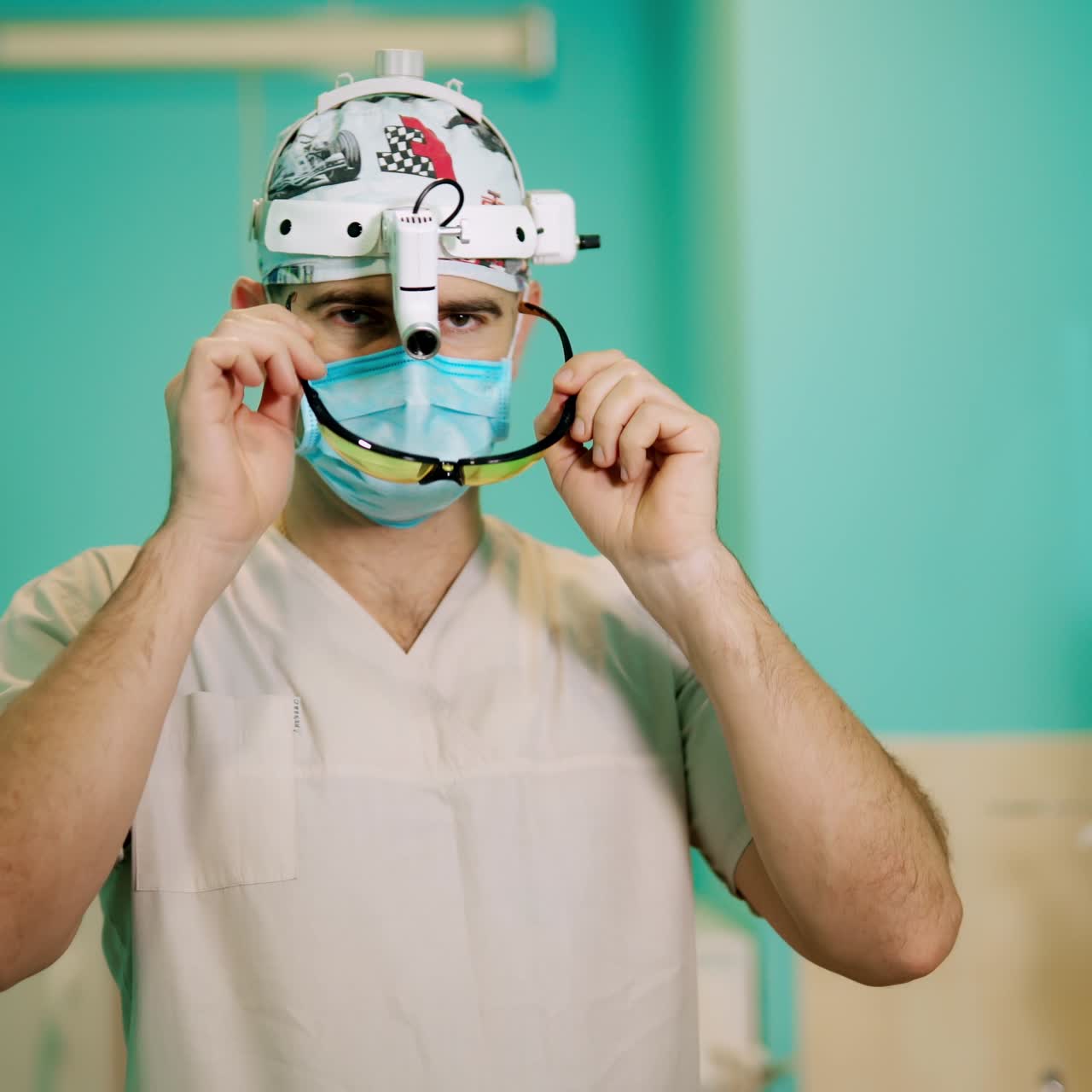 Surgeon before the operation. Portrait of a specialist wearing surgical mask and glasses. Doctor puts on glasses and starts washing hands.