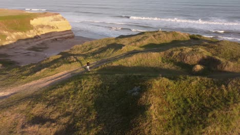 aerial orbiting around photographer taking photos on cliff at mar del plata, argentine