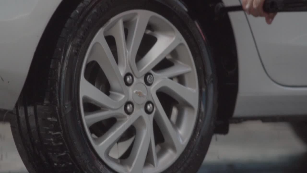 Professional worker cleaning a car tire thoroughly. Slow motion