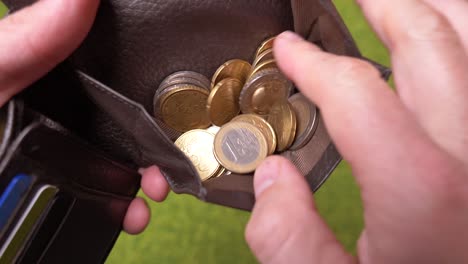 close up shot of male person watching inside wallet purse and counting euro coins