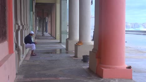 un hombre se sienta bajo una pasarela en la habana cuba refugiándose de una gran tormenta