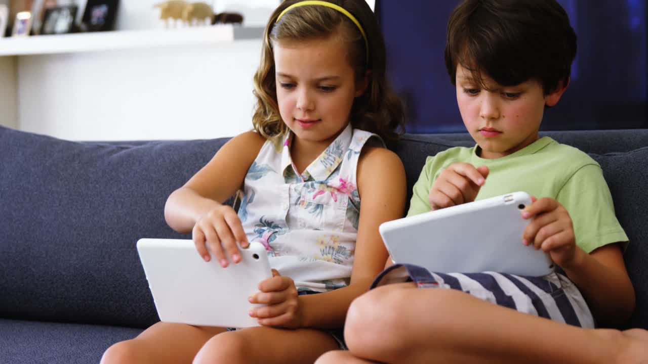 hermanos usando tableta digital en la sala de estar