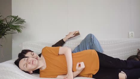 two girls are lying on the couch, kissing and huggin