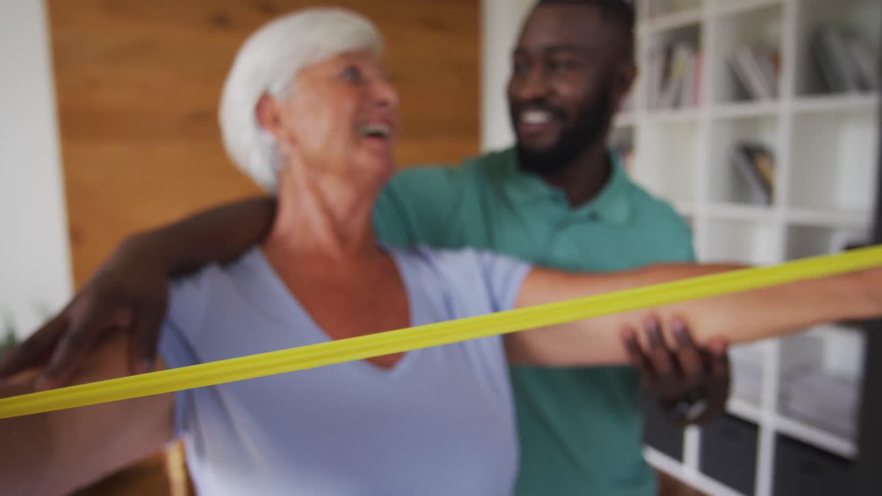 Video di anziana donna caucasica felice che si esercita con fisioterapista maschio afroamericano