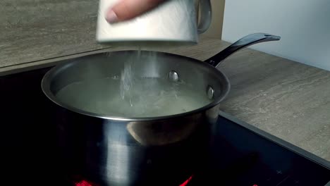 adding puffed rice with boiling water on a electric stove, closeup