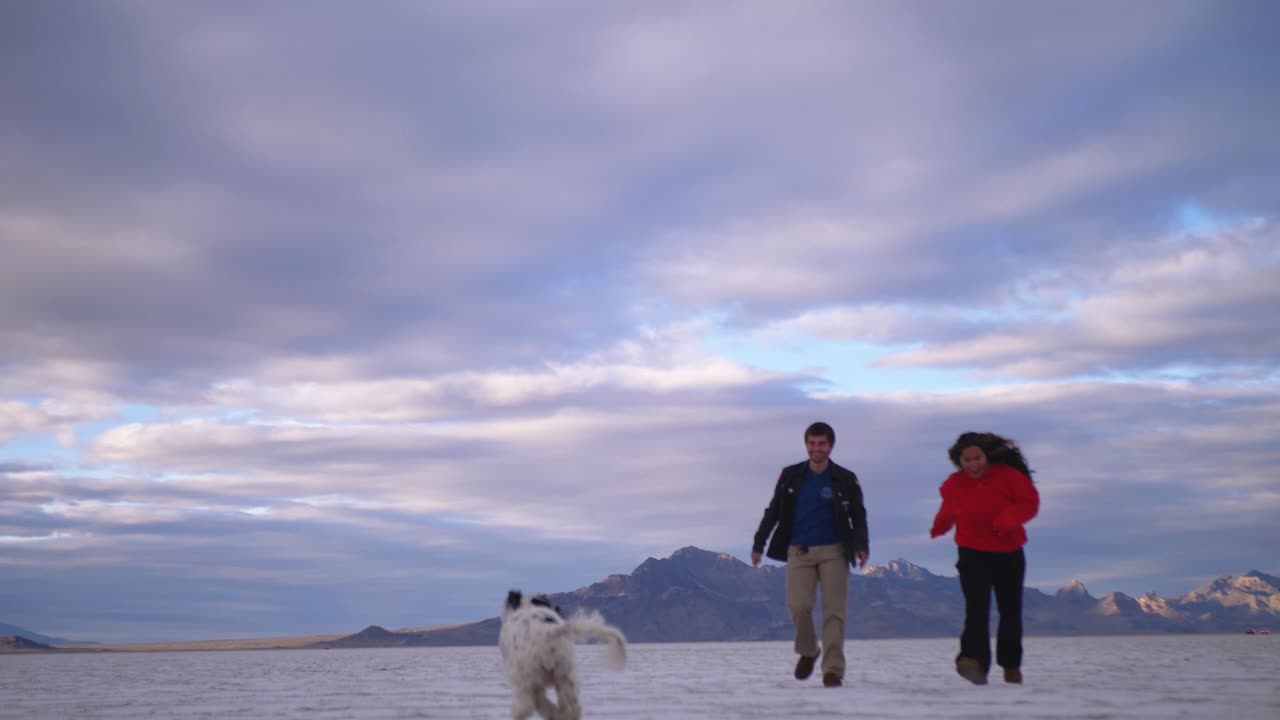 two lovers walk towards the camera in the salt flats during sunset