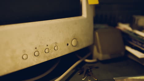 dusty old computer monitor and cluttered desk accessories in a dim room