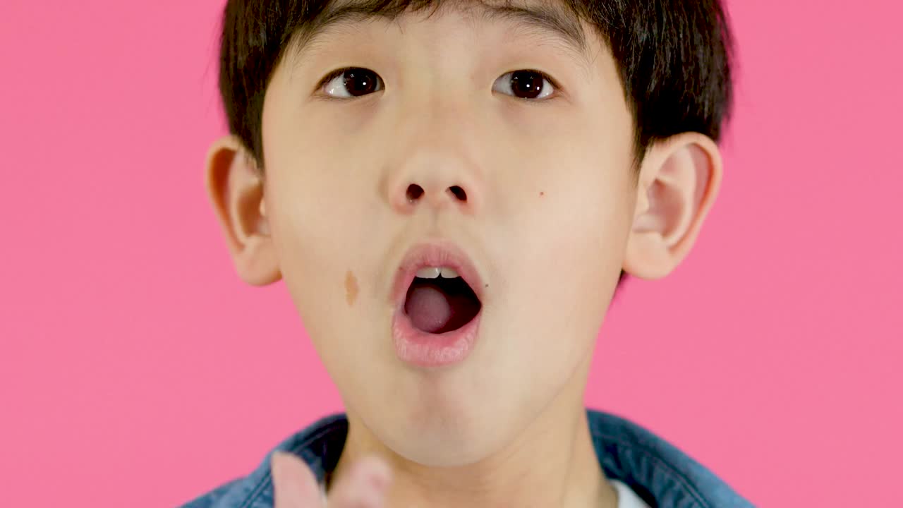 デニムジャケットを着た少年が、両手を添えて興奮して叫んでいる。
