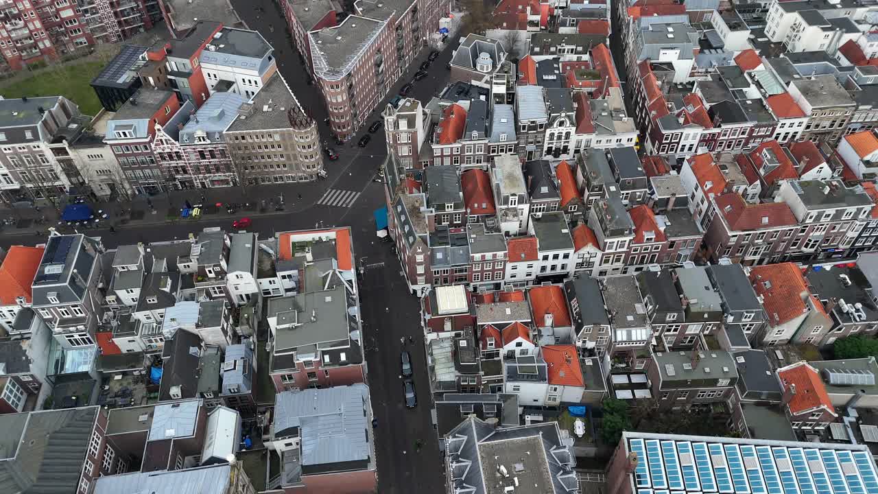 Dutch townhouses and modern apartment block with solar panels in neighborhood of The Hague. Historic city in Netherlands near sea. Renewable energy in town. Aerial top down flyover.