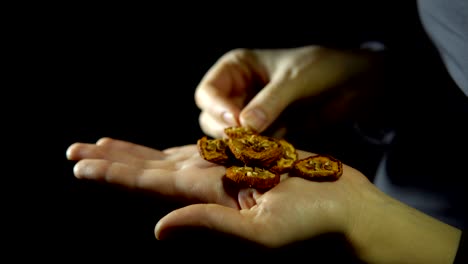 close-up of fingers move a handful of dry apple in hand on a black background.