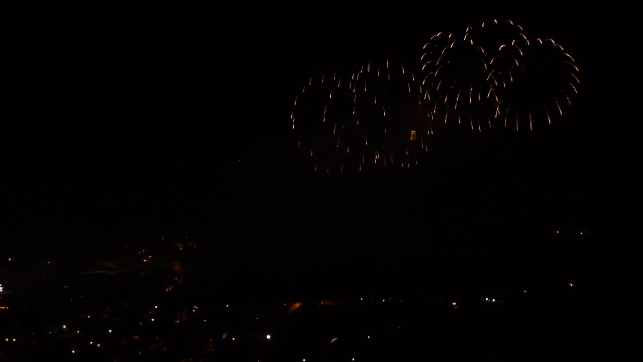 Celebration with colorful and sparkling fireworks, over a mountain town, at night