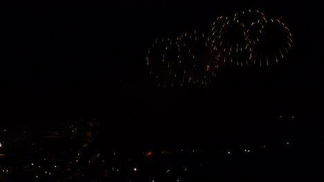 celebration with colorful and sparkling fireworks, over a mountain town, at night