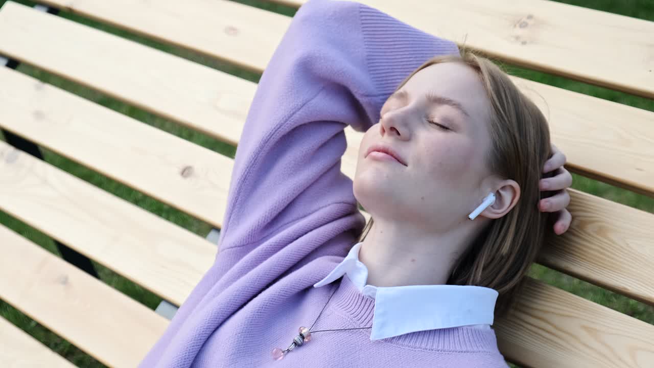 색 무선 헤드폰을 입은 편안한 젊은 여성 금발