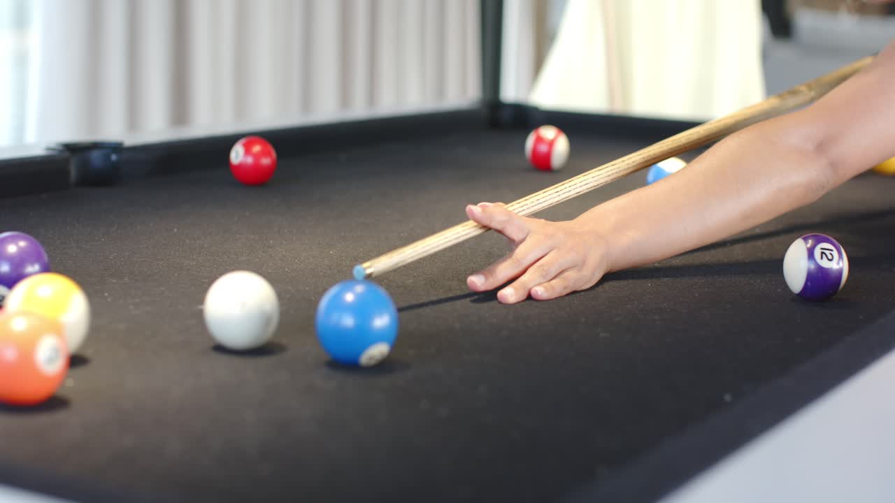 Woman forming bridge lining blue-tip cue hitting cue ball on black-felt table for fun, copy space