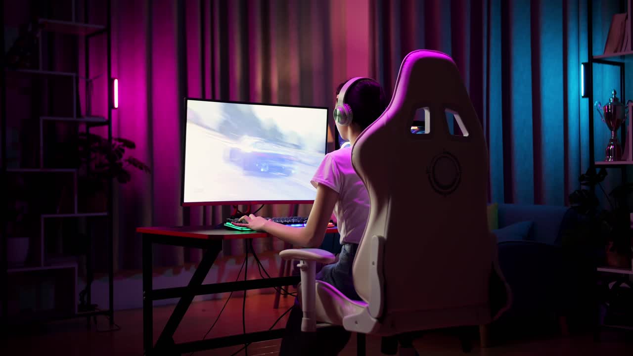 una adolescente asiática emocionada celebra la victoria y baila mientras juega a un videojuego en la computadora, jugando a un juego de carreras