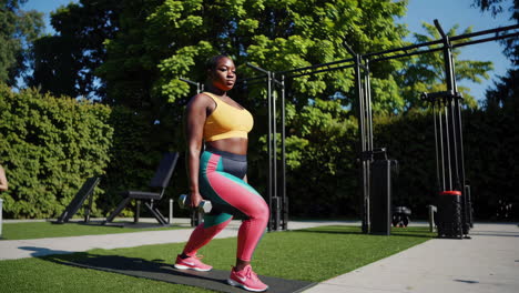 plus-size woman doing lunges with dumbbells outdoors