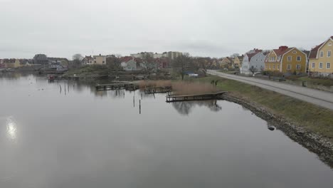 A-scenic-view-of-small-wooden-bridges-on-still-water,-a-group-of-birds,-a-saunaraft-and-the-beautiful-island-Ekholmen-of-Karlskrona,-Sweden-in-the-background