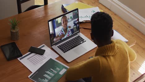 African-american-female-teacher-talking-and-taking-notes-while-having-a-video-call-on-laptop-at-home