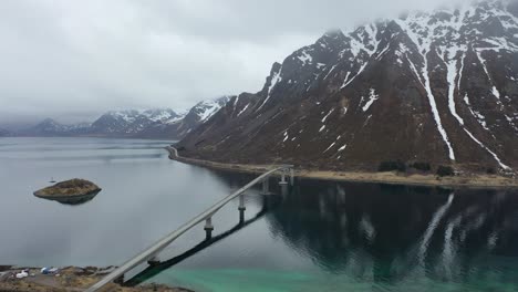 Flying-over-Lofoten-Reine-mountain-peaks-overlooking-picturesque-wintry-blue-ocean