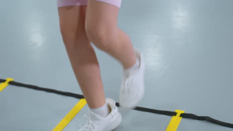niño con camisa rosa realizando ejercicios de fitness entrando y saliendo de la caja mientras otro niño se centra en el entrenamiento en el fondo, esteras de gimnasio, accesorios de entrenamiento y entorno de fitness estructurado