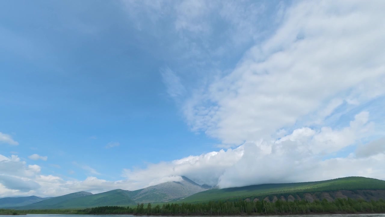 Timelapse of clouds moving over a mountain peak and green forest in Siberia