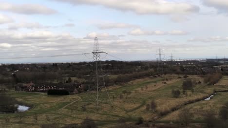 flying electricity distribution power pylon overlooking british parkland countryside, wide rising shot