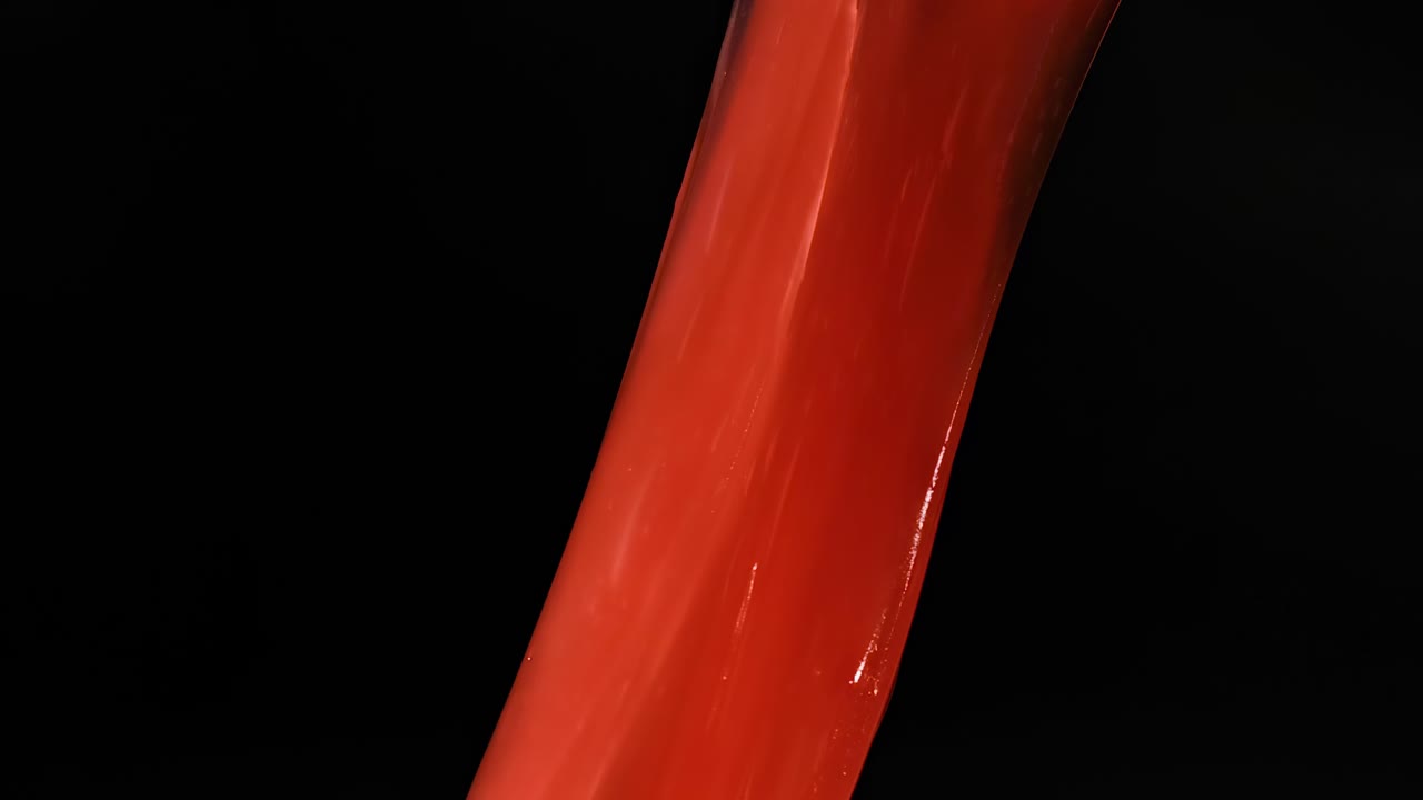 Close-up of hands manipulating and stretching vibrant red slime against a dark background.