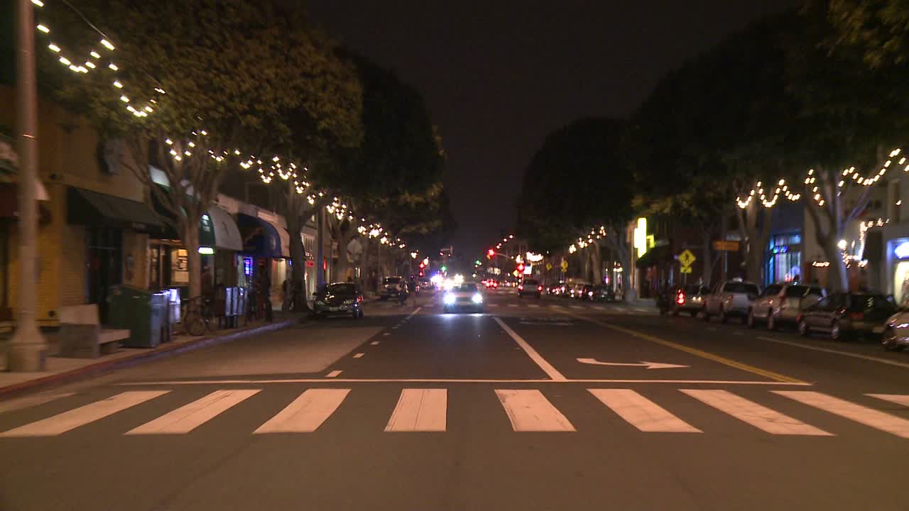 뒷창 3을 통해 보이는 산타모니카 캘리포니아의 밤 거리를 따라 자동차가 이동합니다.