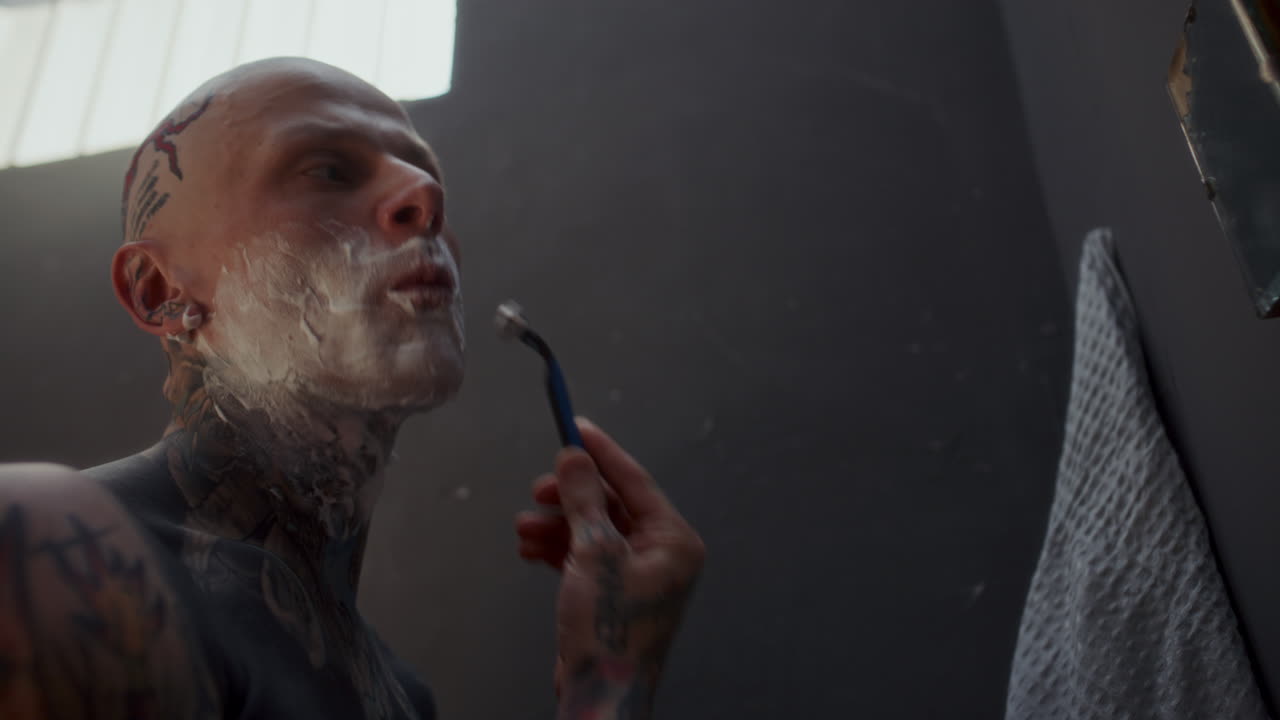 Tattooed Man Shaving His Face during Morning Routine in Prison