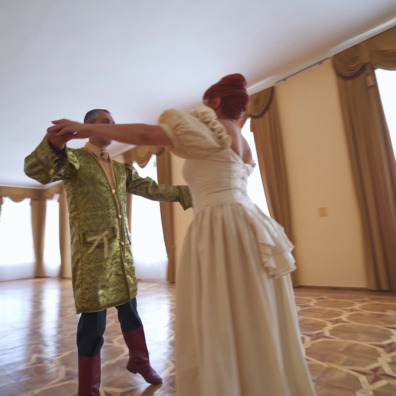 People in historic clothes performing old dance. A couple of adult people dancing in the big empty hall