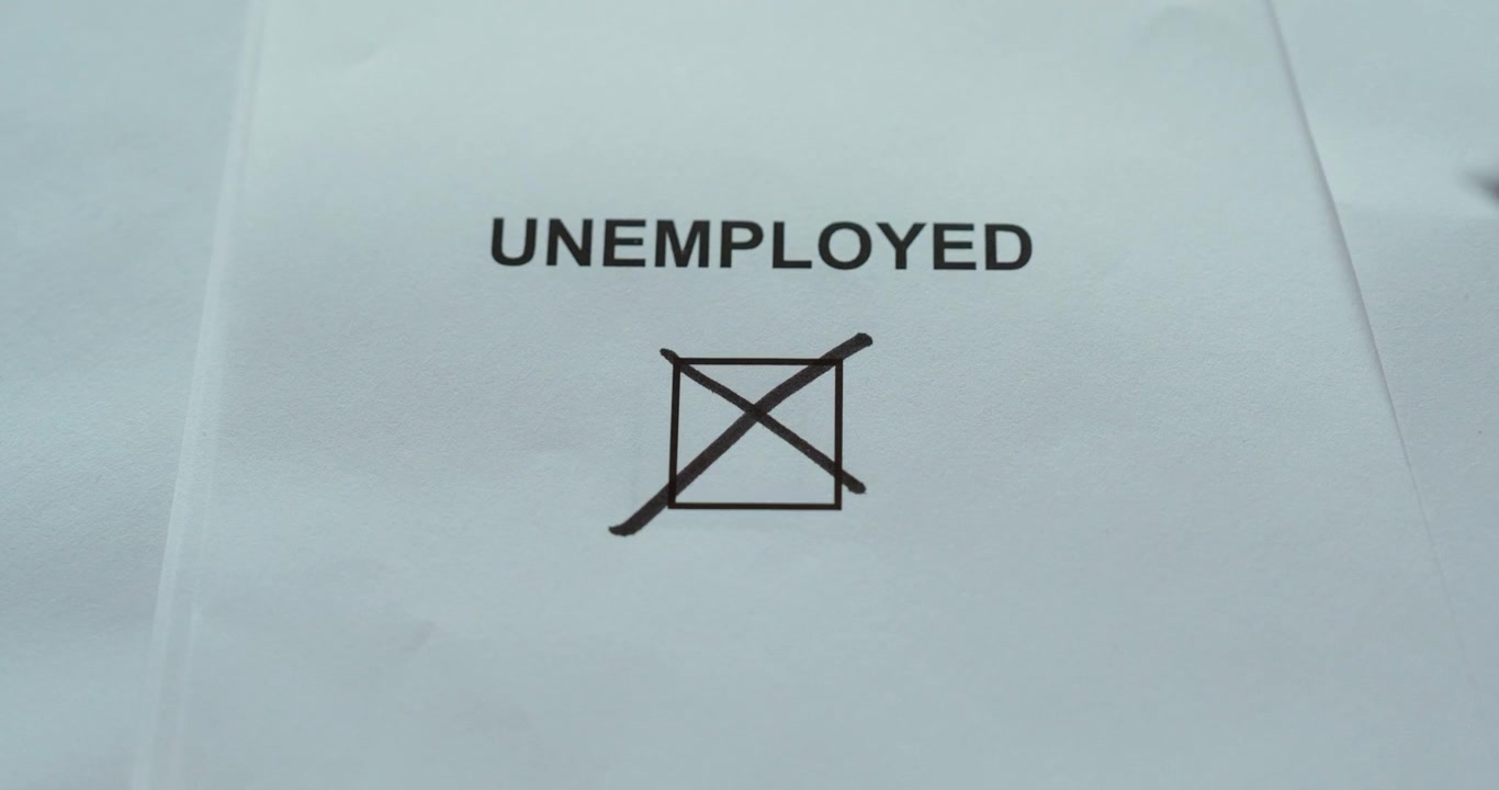 Close-up of a hand marking the unemployed checkbox on a paper form, representing unemployment and job status.