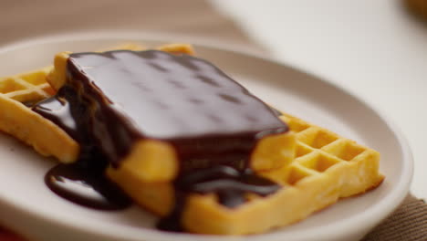 close up of person eating stack of waffles covered in melted chocolate sauce on plate 1