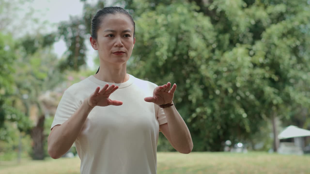 Middle-aged Sportswoman Doing Tai Chi Gymnastics in Park