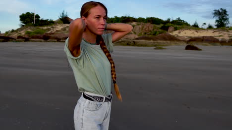 Long-haired-European-female-walking-on-sandy-coastline,-front-view