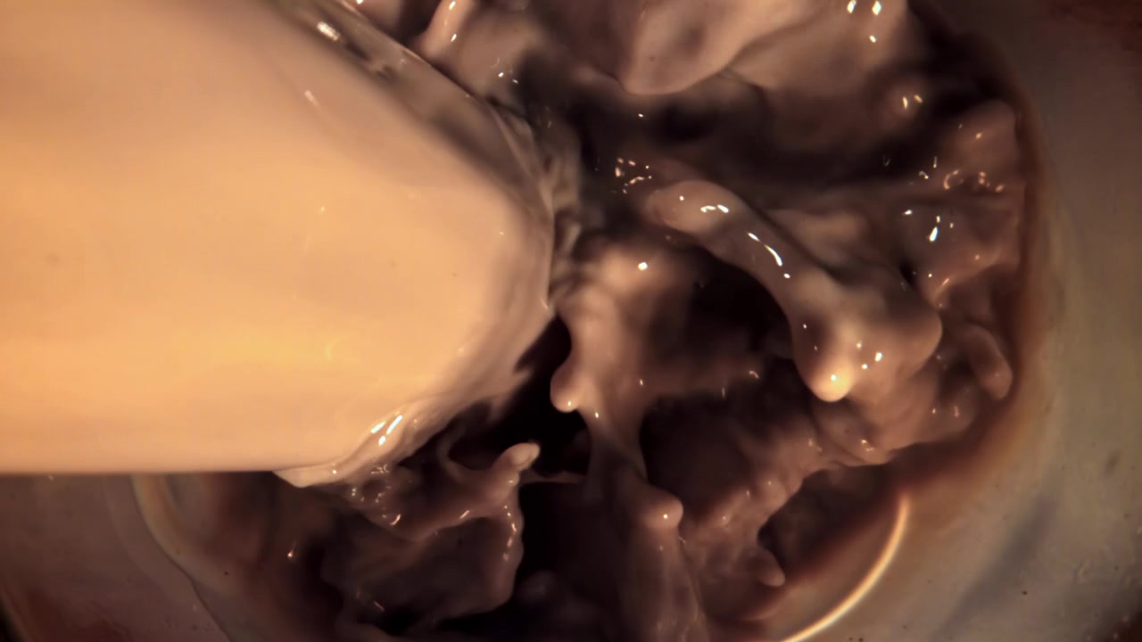 Versamento al rallentatore di latte al cioccolato in un bicchiere