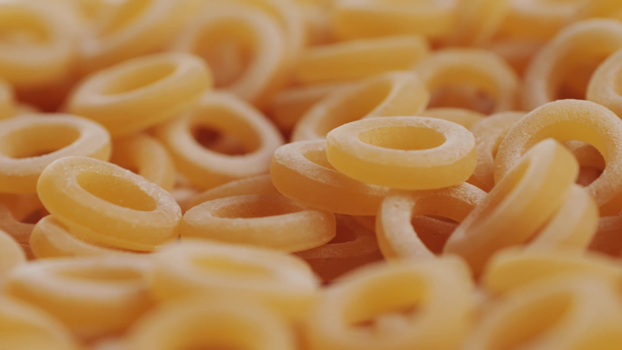 Pasta integrale biologica, maccheroni di semola di grano duro, penne rigate crude in una ciotola di legno. Filmato 4k di alta qualità
