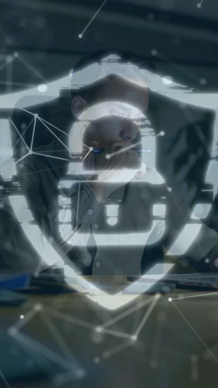 Vertical video: IT pro leaning tapping pen as code streams form shield overlaying him for security