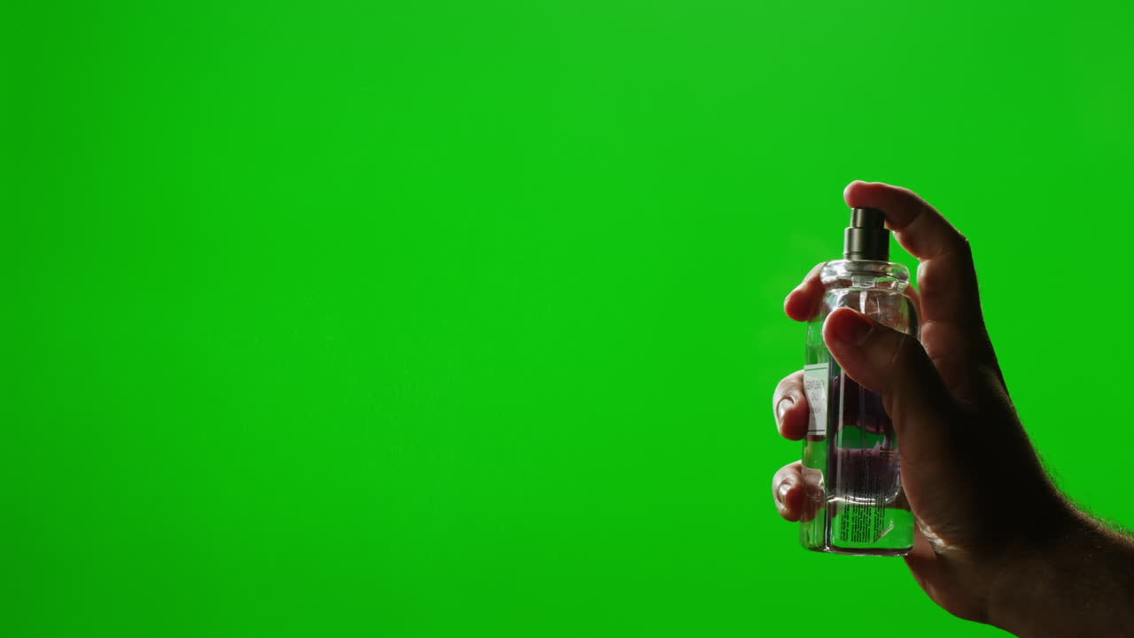 Hand holding perfume bottle spraying