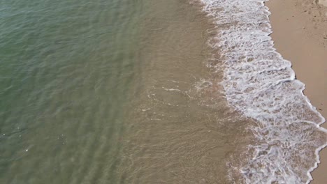 static shot of waves slowly breaking on a white sandy beach