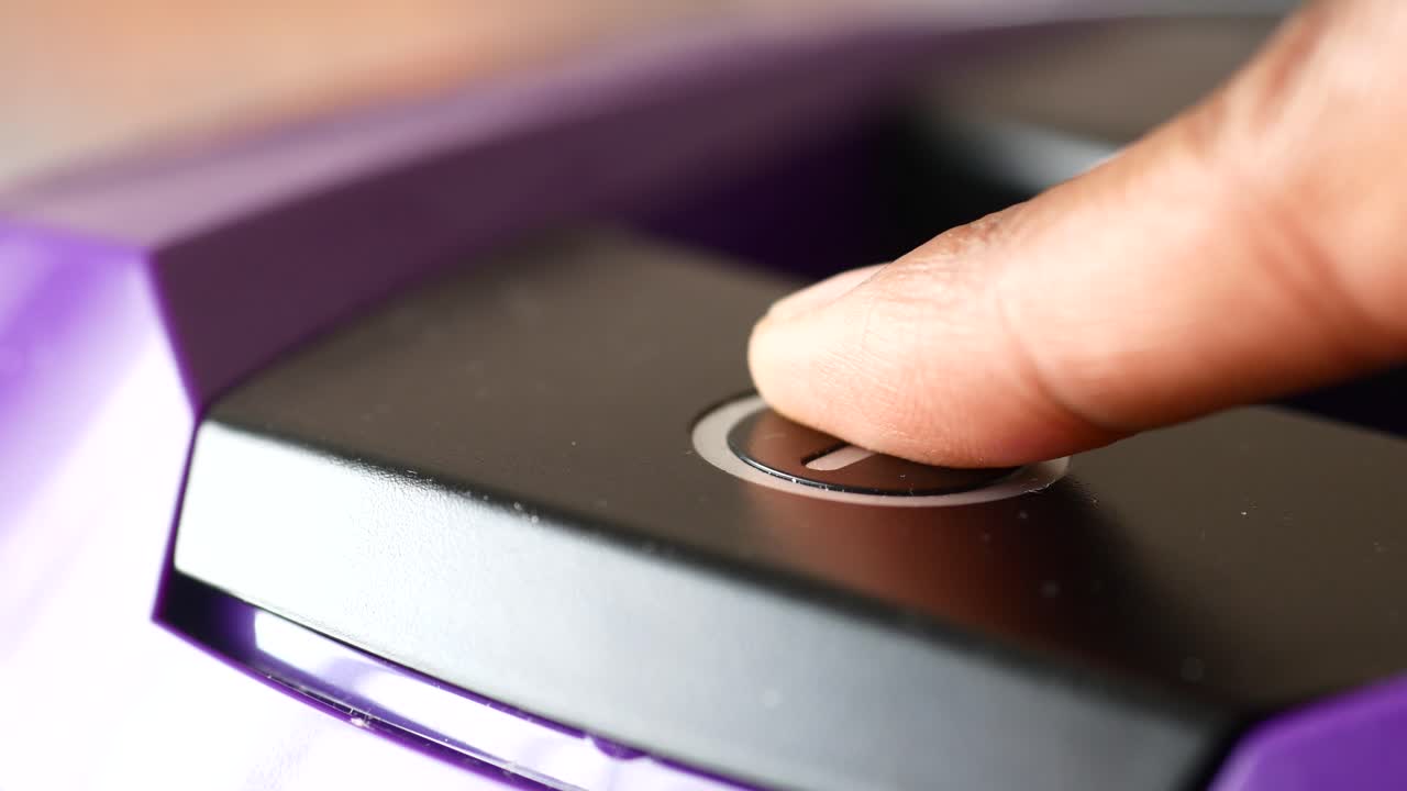 up di un dito che preme il pulsante di accensione su un dispositivo viola