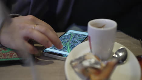 close-up detail of woman using google maps on phone at cafe place