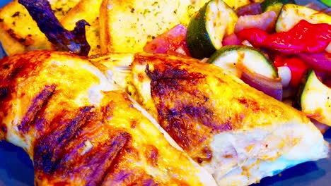 bbq rotisserie closeup plate if chicken breasts legs halves and quarters with grill marks mixed with toasted garlic bread with seasoning and grilled peppers onions zucchini on a ceramic plate at 360