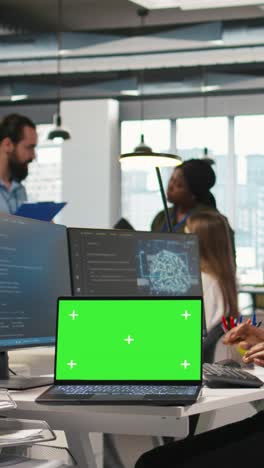 vertical video technician using mockup laptop next to office coworkers developing applications