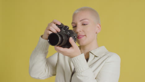 female caucasian model posing with dslr against yellow backdrop 03