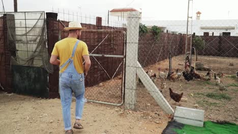 Farmer-man-feeding-hens-in-the-barnyard-through-the-fence