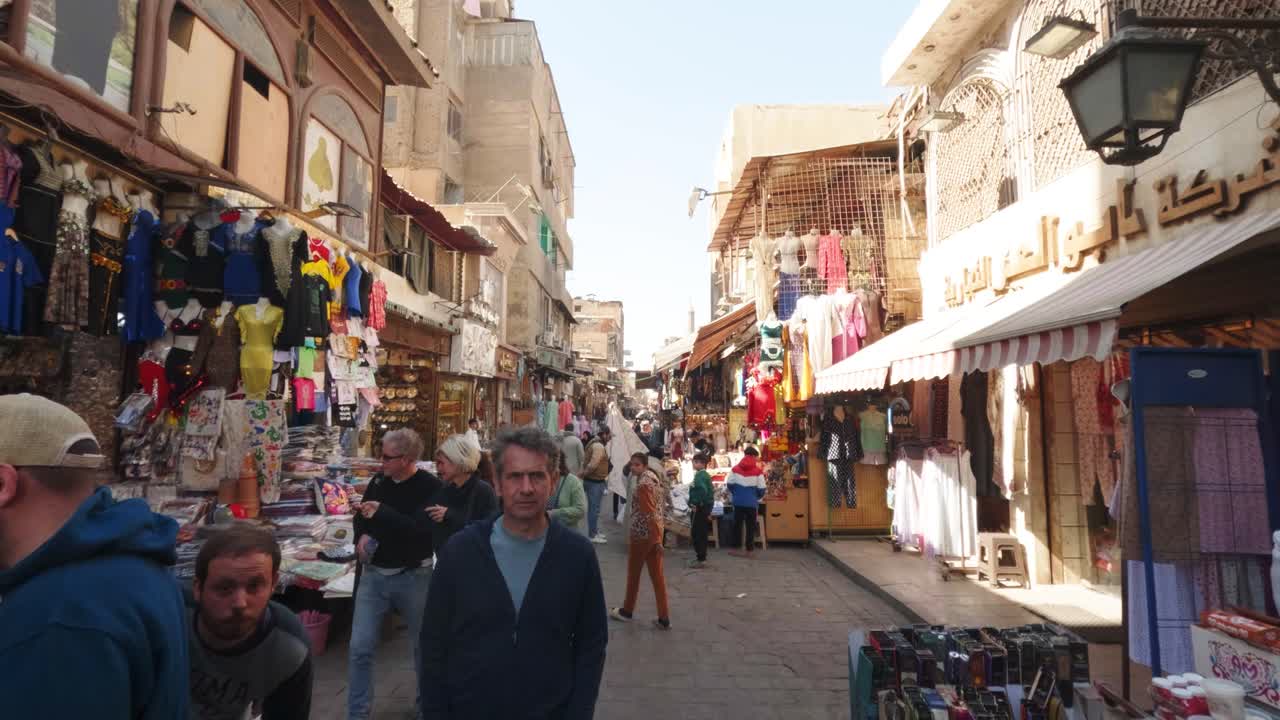 People Walking Through a Bustling Street Market in a Narrow Alley