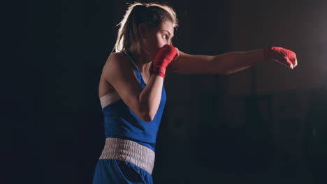 beautiful woman fighter in red bandages conducts a shadow fight while exercising in the gym. slow motion. steadicam shot