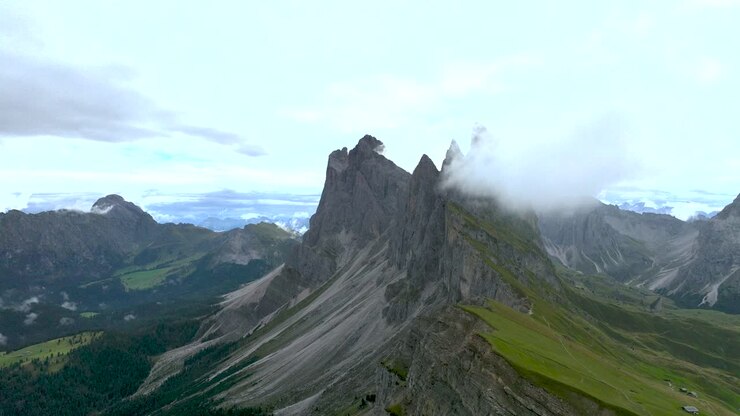 aufsteigende drohnenaufnahmen zeigen die schroffen gipfel mit grünen bergwiesen der dolomiten